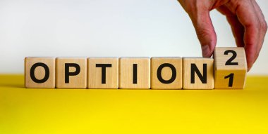 Birinci seçenek ya da ikinci seçenek. El küpü çevirir ve '1' sayısını '2' ya çevirir ya da tam tersi. Tahta küplerde kelime seçeneği. Güzel sarı masa, beyaz arka plan. İş konsepti. Boşluğu kopyala.