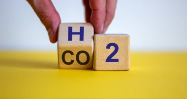 Yakıt hücreli araçlara geçin. Elle bir küp çevirir ve CO2 ifadesini H2 'ye çevirir. Güzel sarı masa, beyaz arka plan. Ekolojik kavram.