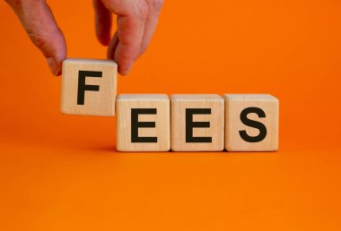 Concept word 'fees' on cubes on a beautiful orange background. Male hand. Business concept. Copy space. clipart