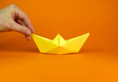Kağıt iten iş adamının görüntüsü origami teknesini kavramsal bir imajda ileriye taşıdı. Fotokopi alanı olan turuncu arkaplan. İş konsepti.