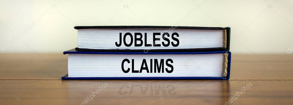 Books with text 'jobless claims' on wooden table. Beautiful white background. Business concept, copy space.