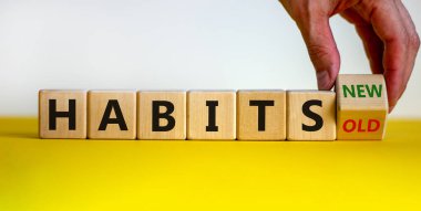 Erkek el küpü döndürür ve 'eski alışkanlıklar' ifadesini 'yeni alışkanlıklar' a çevirir. Güzel sarı masa, beyaz arka plan. Kavram. Boşluğu kopyala.