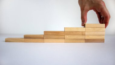 İş büyümesi konsepti başarı süreci. Erkek eli. Tahta bloklar beyaz arka plandaki basamaklar gibi istifleniyor, kopyala uzayı. Fikir ve yenilik kavramı.