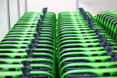 Süpermarketin önünde sıra sıra alışveriş arabaları. Sıraya dizilmiş yeşil alışveriş arabaları..