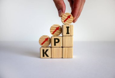 İş büyümesi konsepti başarı süreci. Erkek eli. Tahta bloklar ve 'KPI' sözcüğüyle daireler ve beyaz arka planda basamak olarak istiflenen oklar, boşluğu kopyala.