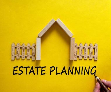 Güzel sarı arka planda 'emlak planlaması' nı el yazısı. Ahşap bir ev modeli. Erkek eli, tahta çit. Uzayı kopyala İş konsepti.