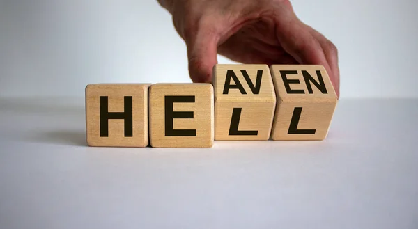 Hell or heaven. Hand turns a cube and changes the word \'hell\' to \'heaven\'. Concept. Beautiful white background, copy space.