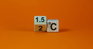 Küresel ısınmayı sınırlamanın sembolü. Küpü çevirdim ve '2 C' ifadesini '1.5 C' olarak değiştirdim, ya da tam tersi. Kavram. Güzel turuncu arkaplan, kopyalama alanı.