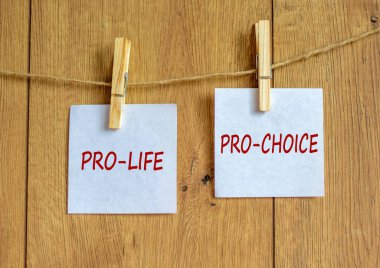 Tahta mandallar ve beyaz kağıtlar. Kürtaj karşıtı, kürtaj karşıtı diye mesaj at. Güzel ahşap arka plan. Kürtaj konseptinde kadın hakları, boşluğu kopyala.