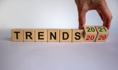 İş planı 2021. Erkek el ahşap küpleri çevirir ve 'TRENDS 2020' yazısını 'TRENDS 2021' olarak değiştirir. Güzel beyaz arkaplan, kopyalama alanı.