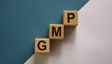 Ahşap küplerin kelime 'GMP, iyi üretim pratiği' basamak basamak basamakları mavi ve beyaz arka plan, kopyalama alanı. İş konsepti.