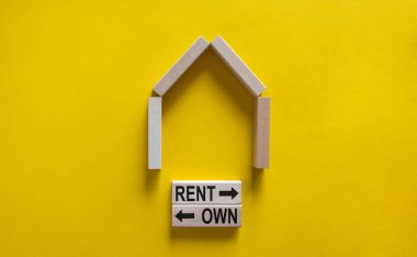 Ahşap bir ev modeli. Tahta bloklardaki kelimeler, kiradır ve oklardır. Uzayı kopyala İş konsepti. Güzel sarı arkaplan.