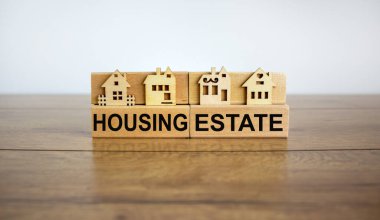 Tahta bloklar konut, minyatür ev, ahşap masa kelimelerini oluşturur. Güzel beyaz arka plan, kopyalama alanı. İş konsepti.