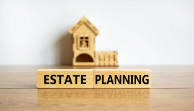 Bloklar, minyatür bir evin önünde mülk planlama kelimelerini oluşturur. Güzel ahşap masa, beyaz arka plan. Boşluğu kopyala.