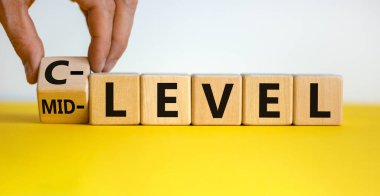 Orta seviyeden C seviyesine. El küpü döndürür ve 'orta seviye' kelimesini 'C seviyesi' olarak değiştirir. Güzel sarı masa, beyaz arka plan, kopyalama alanı. İş konsepti.