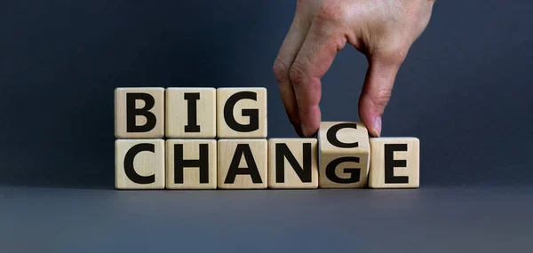 Hand flips a cube and changes the words \'big change\' to \'big chance\'. Beautiful grey background, copy space. Business concept.