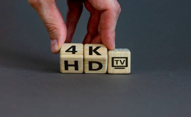 HD TV 'den 4K TV' ye geçişin sembolü. Erkek eli. Güzel gri arkaplan, kopyalama alanı.