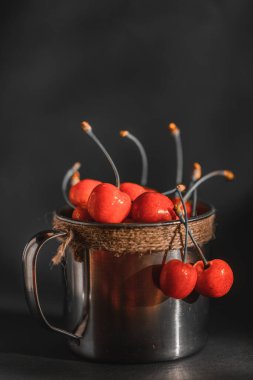 Eski metal bir bardakta taze organik kiraz. Köy arka planında eski metal bardakta olgun ve sulu kirazlar. Seçici odaklanma. Sığ alan derinliği.