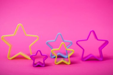 Pembe arka planda yıldız şeklinde kurabiye yapmak için mavi ve sarı renkli plastik kalıplar. Mutfak ya da parti konsepti. Kopyalama alanı ile düz uzandı.