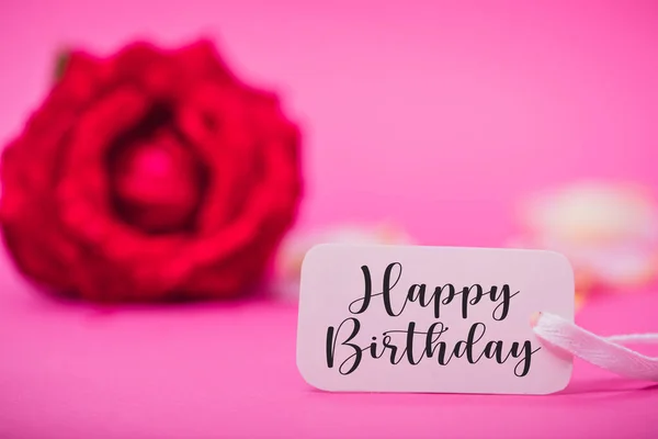 Birthday background with flowers and card. Rose and happy birthday word on white card. Pastel colors on selective focus image.