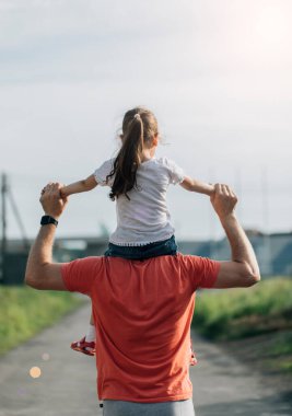 Babası güneşte kızıyla omuzlarında dans ediyor. Babam gün batımında omuzlarında bebekle seyahat eder. Ailesi olan çocuk gün batımında yürür. Mutlu Babalar Günü konsepti.