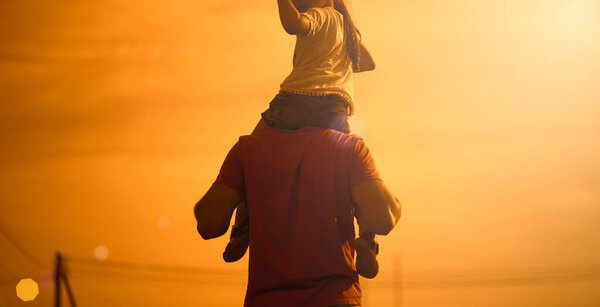 Fathers day concept. Father and daughter meet the sunset. He will put the girl on his shoulders and hold her hands.