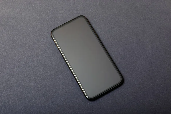 黒の石のテーブルの背景に空白の画面を持つ黒の近代的な携帯電話 古いダークグレーのヴィンテージテクスチャの背景にスマートフォン トップ表示 テキストのコピースペース — ストック写真