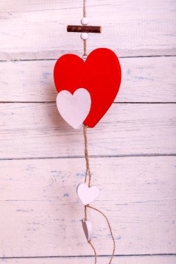 Boyanmış beyaz tahtalarda asılı kırmızı romantik ahşap bir kalp. Kalpler ipte sallanıyor. Sevgililer Günü tebrik kartı. Aşk konsepti