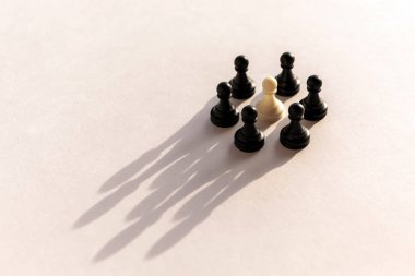 Beyaz arka planda taç şeklinde gölgesi olan plastik satranç piyonu çemberi. Takım çalışması, grup anlaşması ve başarı kavramı