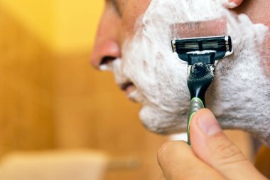 Tıraş köpüğüyle yüzünü tıraş eden bir adam. Erkekler cilt bakımı kavramı.