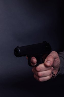 Siyah arka planda silahlı bir erkek. Silahlı adam ateş etmeye hazır, silaha odaklan..