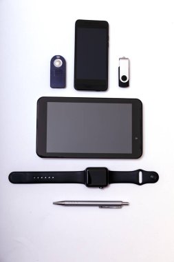 İş ya da eğitim geçmişi. Tablet, telefon, kalem, kalem, beyaz arka plan. Beyaz masada siyah ve gümüş aksesuarlar, üst görünüm.