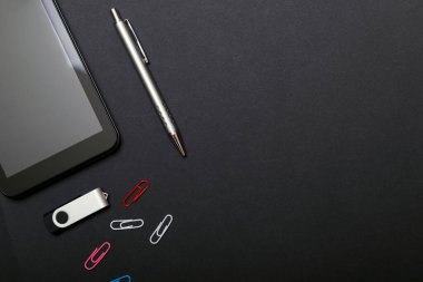 İş yeri, tablet bilgisayar ve akıllı telefon siyah masada. Siyah masadaki siyah aksesuarlar, üst görünüm