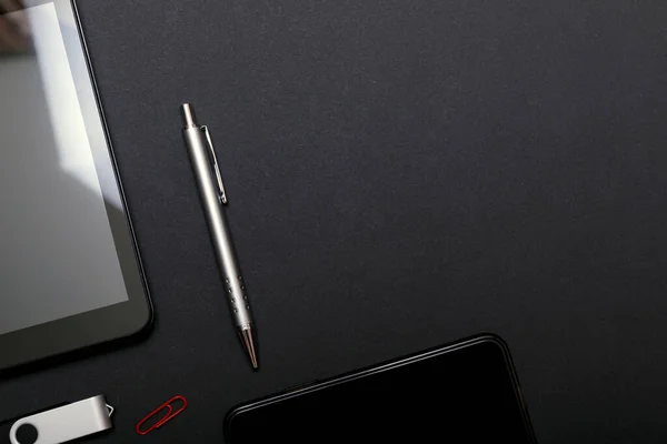 タブレットPcと黒のテーブルの上のスマートフォン 黒いテーブルの上の黒いアクセサリーのセット トップビュー — ストック写真