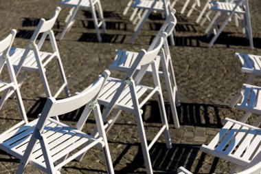 Aşkın simetrisi: Yazın bir düğün töreninden önce çimenlikte beyaz katlanır sandalyeler. Açık havada Çiçekli Beyaz Katlanan Sandalyeler