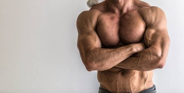 Vücut geliştirici stüdyoda kaslarını esnetiyor. Beyaz arka planda çekici erkek vücut geliştiricisinin gövdesi..