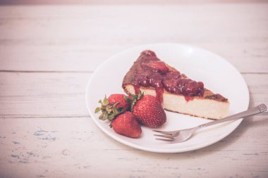 Brownie cheescake, beyaz ahşap masada mükemmel bir şekilde yerleştirilmiş çilekli..