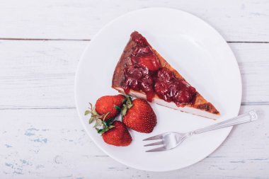 Brownie cheescake, beyaz ahşap masada mükemmel bir şekilde yerleştirilmiş çilekli..