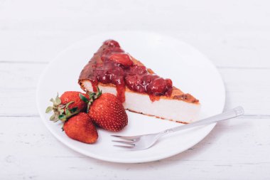 Brownie cheescake, beyaz ahşap masada mükemmel bir şekilde yerleştirilmiş çilekli..