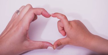 Aşk ellerindedir. Anne ve çocuğun elleri, beyaz arka planda birlikte kalp şekli oluşturuyor. Dünya insani yardım günü konsepti.
