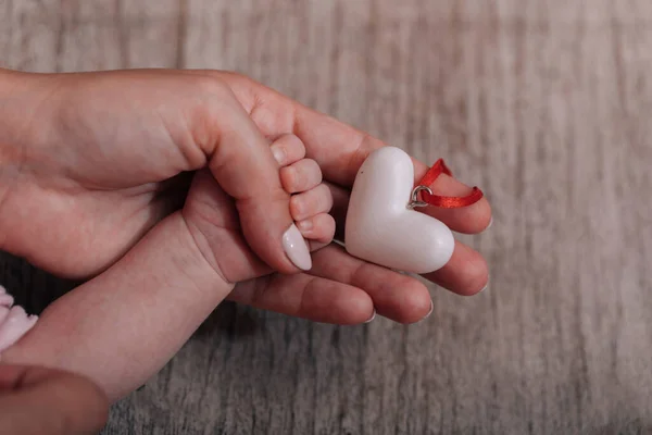Women's hands holding the child's hand with a heart. Place for text. World humanitarian day. The concept of motherhood, caring, family, protection, love.