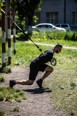 Çekici, güçlü bir adam, Trx fitness kayışlarıyla çaprazlama şınav çeker..