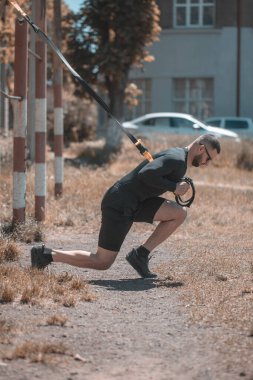 Çekici, güçlü bir adam, Trx fitness kayışlarıyla çaprazlama şınav çeker..