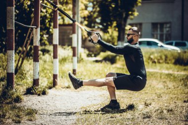 Trx fitness kayışlarıyla şınav çeken bir adam. Açık hava, egzersiz, eğitim, yaşam tarzı konsepti.