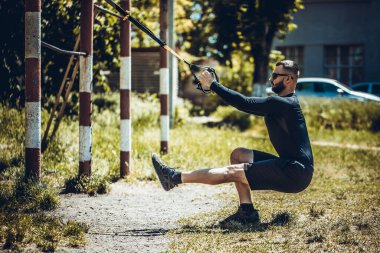 Trx fitness kayışlarıyla şınav çeken bir adam. Açık hava, egzersiz, eğitim, yaşam tarzı konsepti.