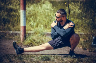 Genç adam koşmadan önce geriniyor. Fitness ve yaşam tarzı konsepti. Genç adam dışarıda yoga egzersizi yapıyor. Meditasyon ve rahatlama.