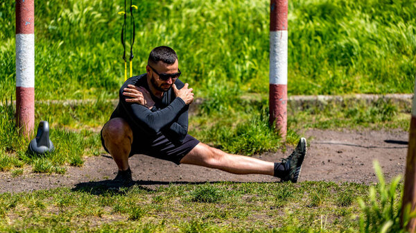 Fit man stretching outside, view at sea. Fitness and sport concept. Man doing yoga outdoor.