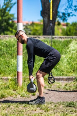 Atletik adam sokak spor salonunda bir çaydanlıkla çalışıyor. Güç ve motivasyon. Açık hava egzersizi..