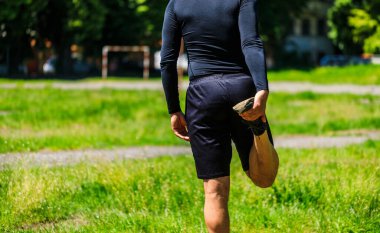 Genç sporcu parkın açıklarında geriniyor. Erkek koşucu dışarıda koşmak için ısınmaya hazır. Fitness yürüyüşü ve sabah yaya yolunda egzersiz. Refah ve spor kavramları