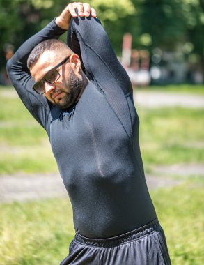 Parkta esneme hareketleri yapan bir adamın spor aktivitesi. Bir sporcunun sağlıklı alışkanlıkları..